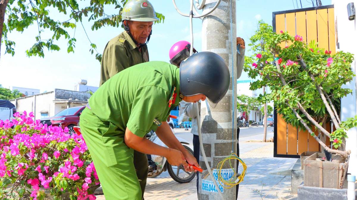 Các cán bộ chiến sĩ và người dân tham gia ra quân bóc gỡ quảng cáo trái phép và làm sạch môi trường tại xã Phước Hải. Ảnh: Minh Tài