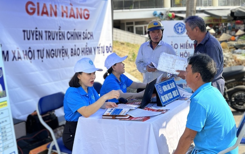 Nhân viên BHXH xã hội Đà Nẵng tư vấn chính sách cho người dân và tiểu thương tại chợ Tam Kỳ. Ảnh: Hoàng Bin