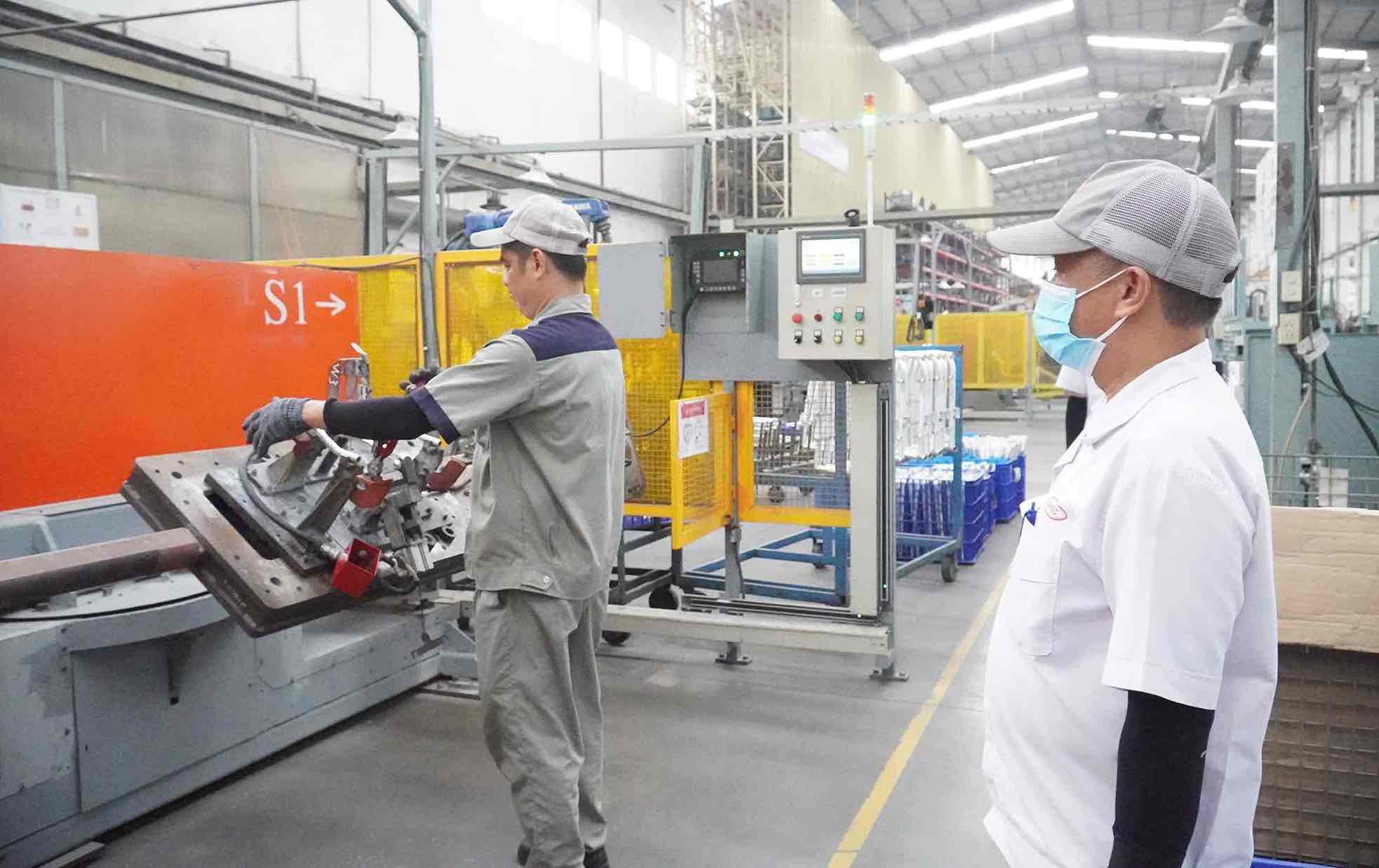 Mr. Nguyen Sy Nguyen, Consultant of Global Dynamics Mechanical Co., Ltd. (right) is supervising workers operating machinery. Photo: HAC