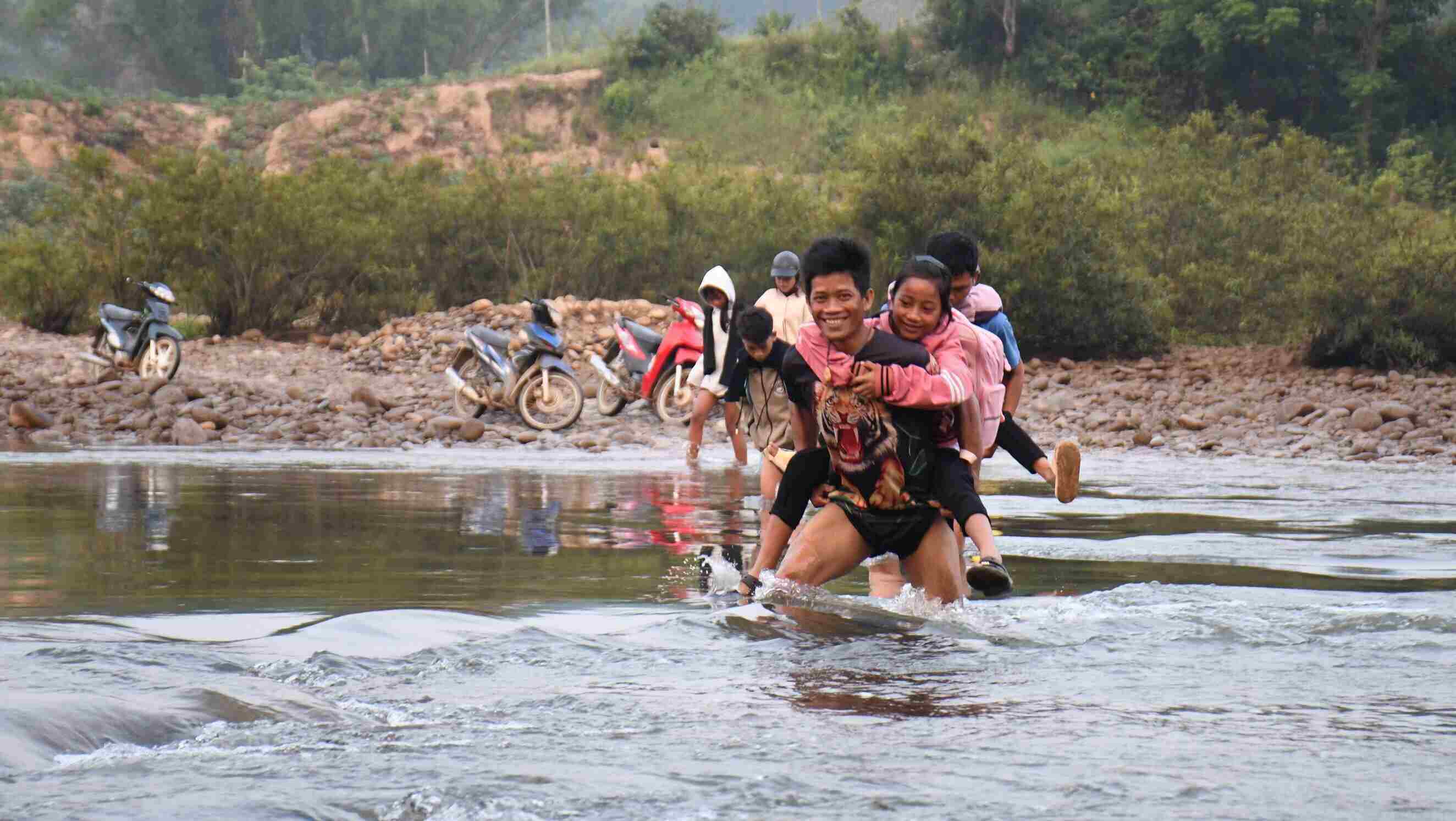 Parents in Lang Trang village, Son Thuy commune, Quang Ngai province carry their children across the river to school. Photo: Dong Giang