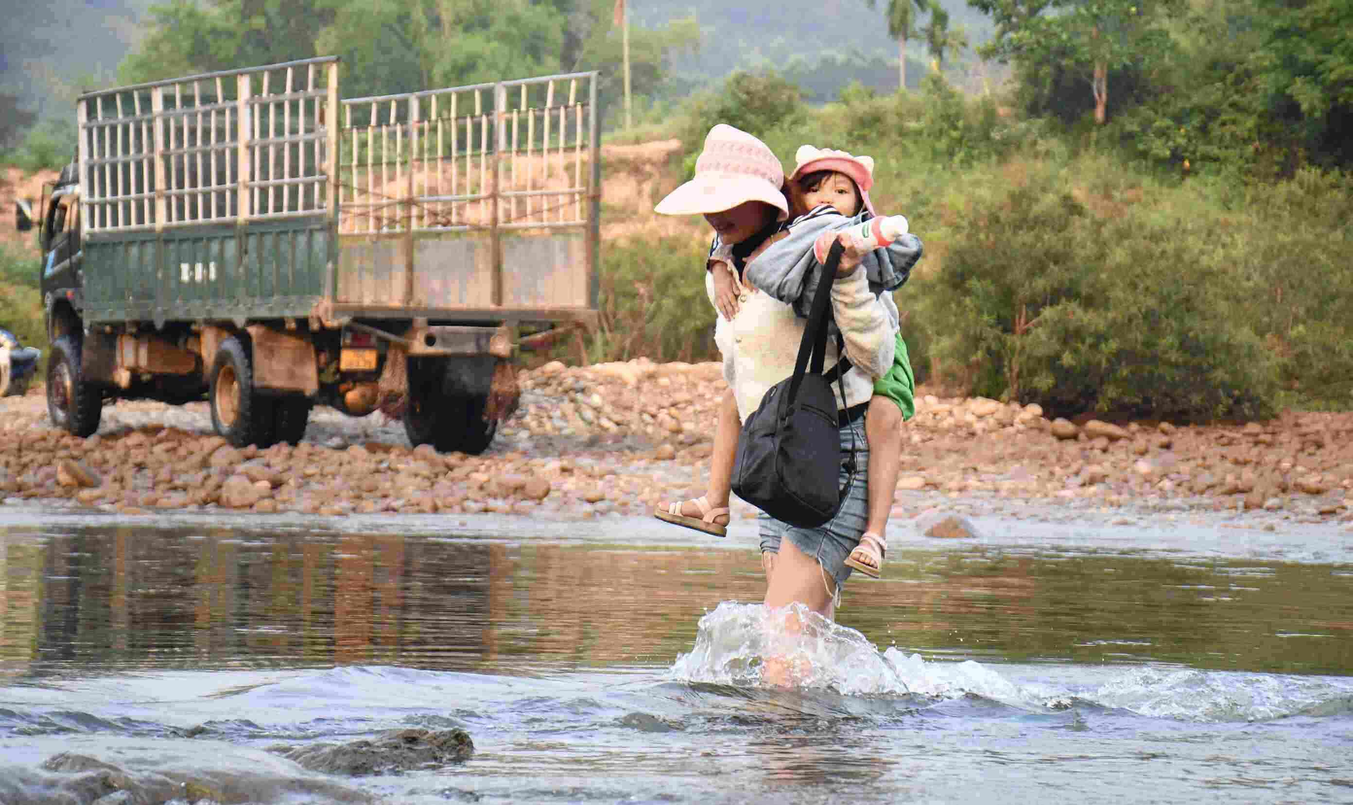 Mỗi ngày, chị Đinh Thị Thiết ở xã Sơn Thủy lại cõng con vượt sông đến lớp trong hành trình đầy vất vả. Ảnh: Đông Giang