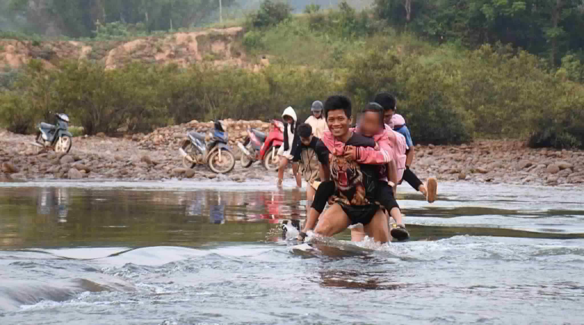 Parents in Lang Trang village, Son Thuy commune, Quang Ngai province carry their children across the river to school. Photo: Dong Giang