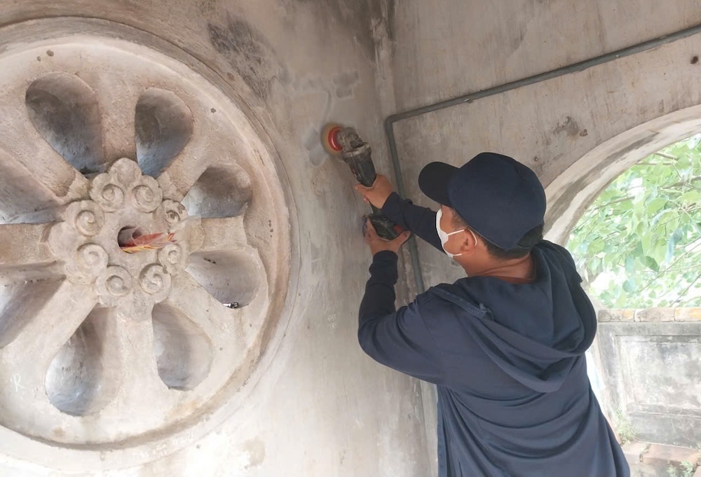 Lực lượng chức năng xóa bỏ các nét vẽ, chữ viết khắc trên Quảng Bình Quan. Ảnh: Nguyễn Luân
