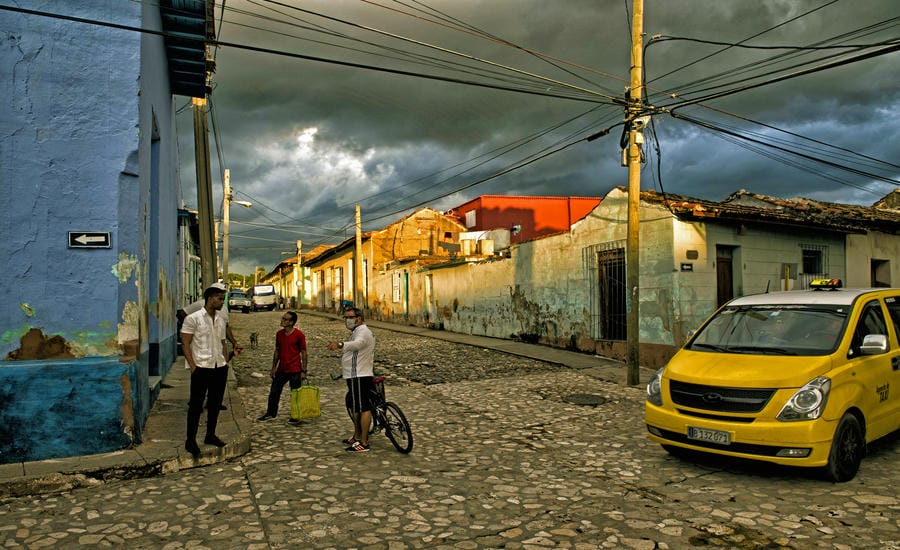 Người dân trò chuyện trên một con phố lát đá tại thành phố cổ Trinidad (Cuba), trong ánh chiều muộn khi cơn mưa dường như sắp đến. Ảnh: Việt Văn