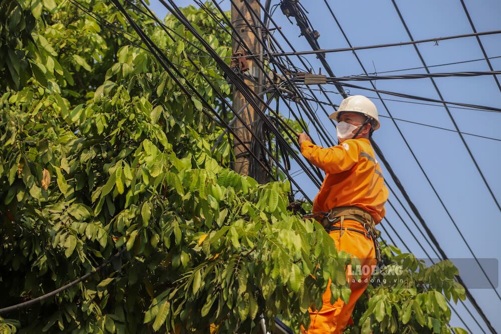 Electricity workers handle overlapping cables, lying down on the road. Photo: Nguyen Luan