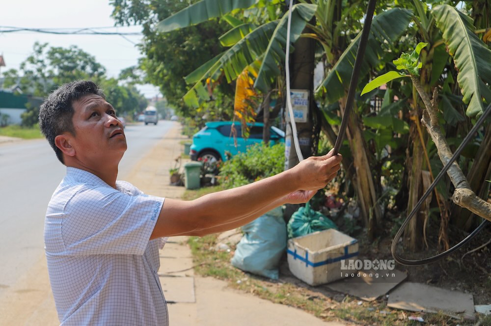 Lực lượng chức năng kiểm tra tình trạng dây cáp viễn thông buông thỏng xuống đường. Ảnh: Nguyễn Luân