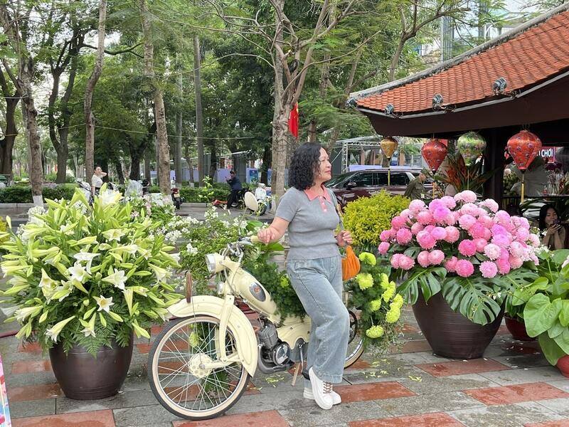 Người dân thành phố diện áo dài, háo hức check-in tham quan chụp ảnh xung quanh vườn hoa và nhà hát thành phố dịp Lễ hội Hoa Phượng Đỏ 2026. Ảnh: Tường Vy