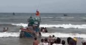 Des centaines de personnes aident à ramener à terre un bateau de pêche échoué à Quảng Trị. Photo: Police de la commune de Nam Trạch