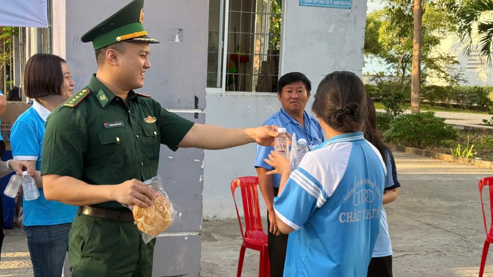 Cán bộ đồn Biên phòng Vĩnh Nguơn phát thức ăn nhanh, hỗ trợ cho các em thí sinh ở điểm thi trường THPT Châu Thị Tế, phường Vĩnh Tế. Ảnh: Biên phòng cung cấp