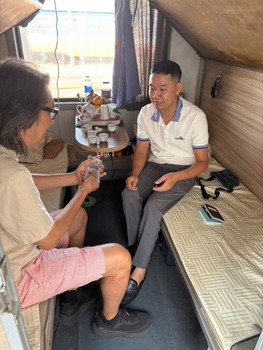 Hành khách (bên phải) nhận lại túi xách chứa tiền và hộ chiếu bỏ quên trên tàu từ nhân viên đường sắt. Ảnh: VNR