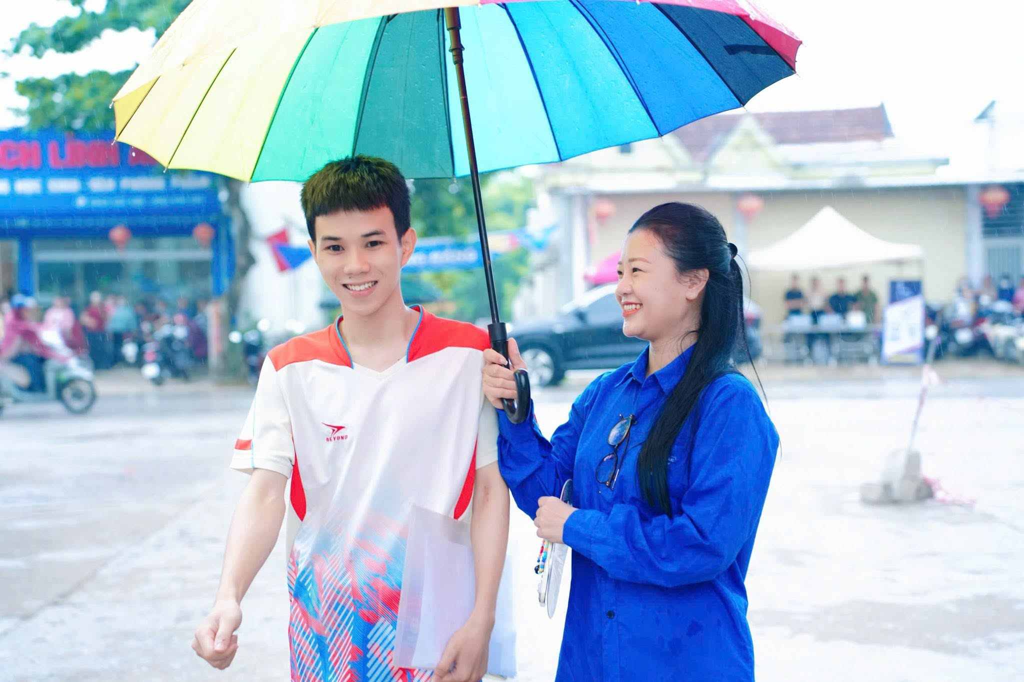 Voluntarios cubren con paraguas y ayudan a los candidatos en los centros de examen en el programa "Apoyo a la temporada de exámenes" 2026 en Nghệ An. Foto: Ngọc Anh