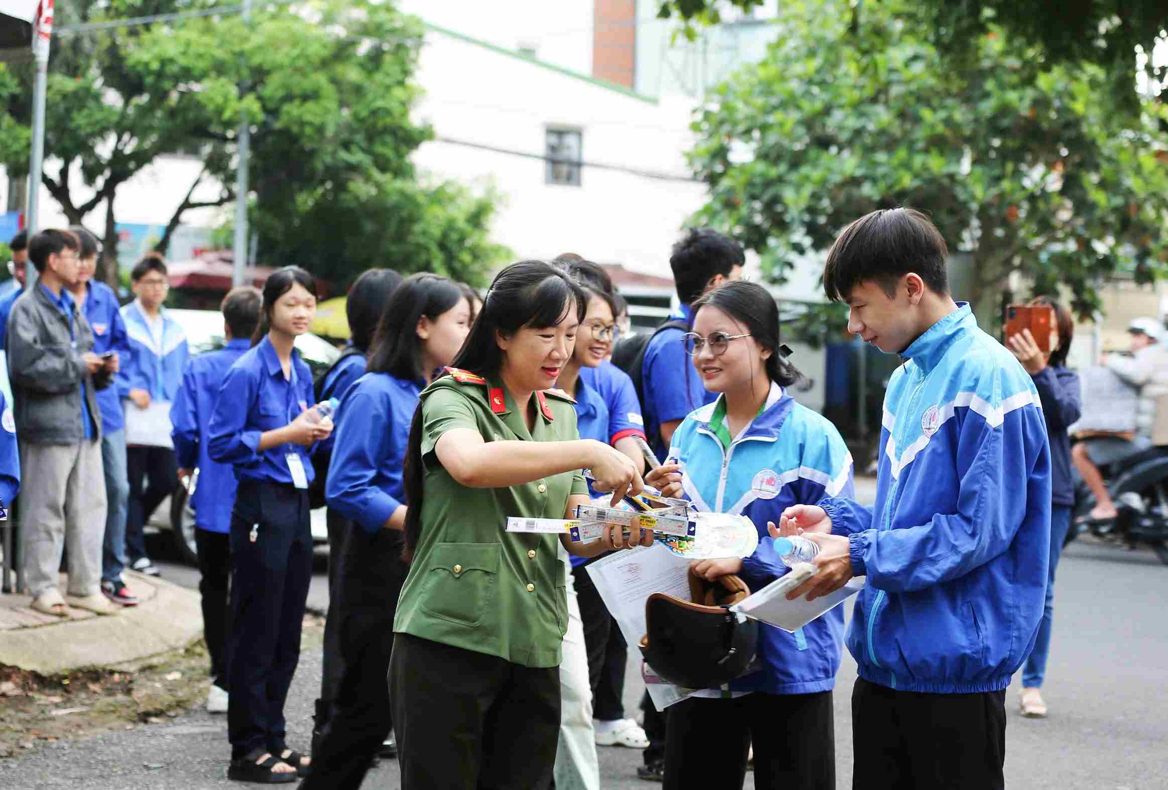 Cán bộ, chiến sĩ Công an phường 2 Bảo Lộc cùng thanh niên tình nguyện tiếp sức cho thí sinh tại điểm thi trường THPT Nguyễn Du. Ảnh: Phúc Khánh 