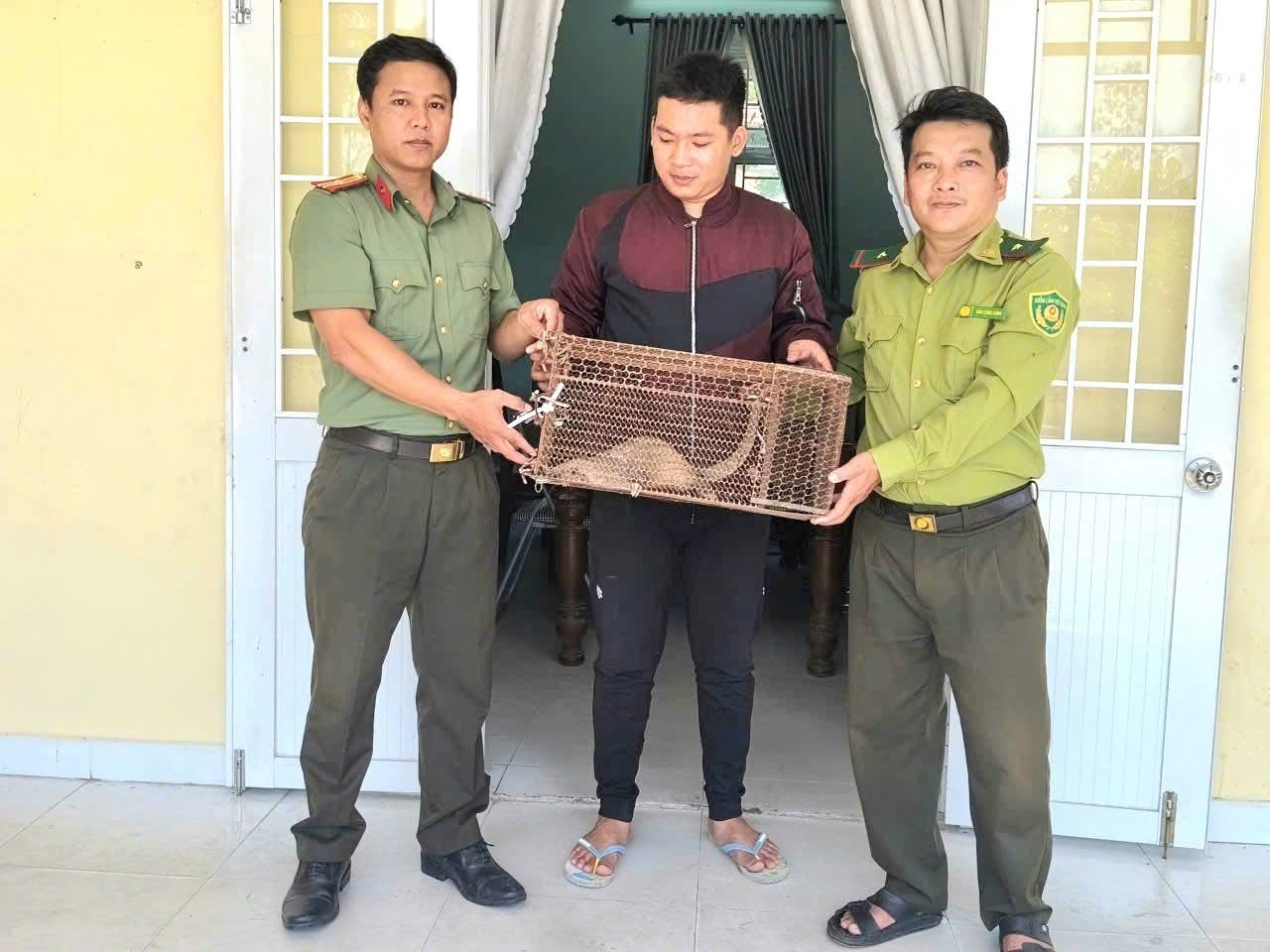 The pangolin individual was discovered by Nguyen Thanh Hien (middle) and handed over to the police and forest rangers. Photo: Dong Tra Bong Commune Police