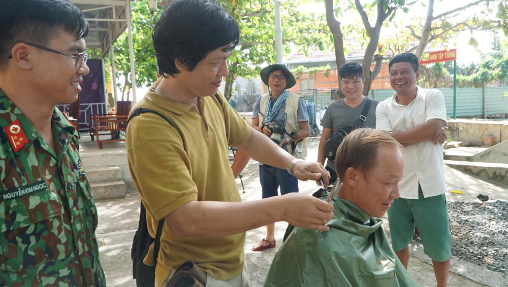 Nhà báo cắt tóc cho cán bộ, chiến sĩ trên đảo Trường Sa Đông. Ảnh: CAO TUÂN
