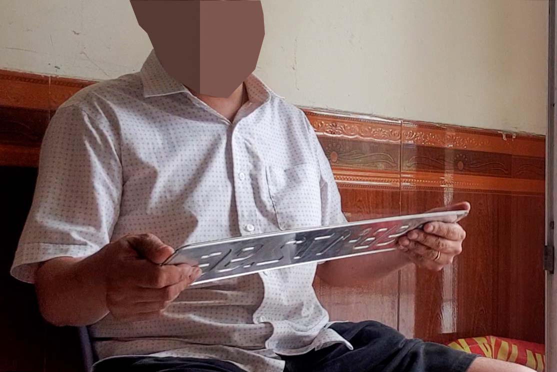 Thợ làm biển số xe giả mang mẫu sản phẩm đến cho khách xem hàng. Ảnh: Nhóm phóng viên.