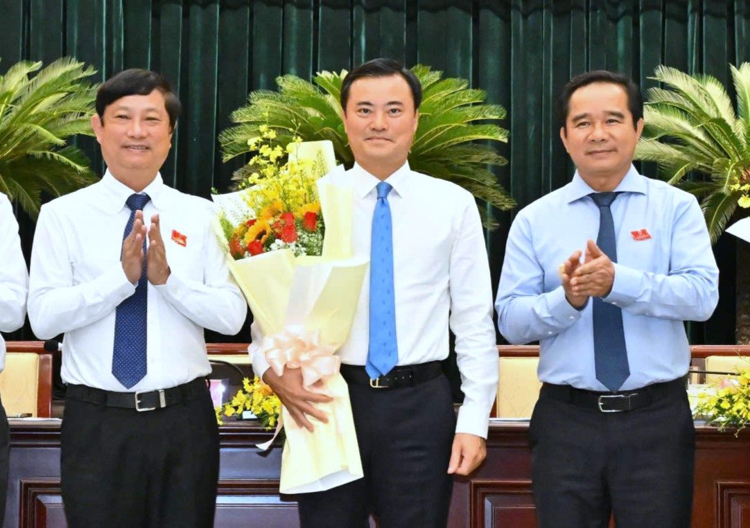 Chairman of Ho Chi Minh City People's Committee Nguyen Van Duoc (right cover) and Chairman of Ho Chi Minh City People's Council Vo Van Minh present flowers to Mr. Bui Xuan Cuong. Photo: Viet Dung