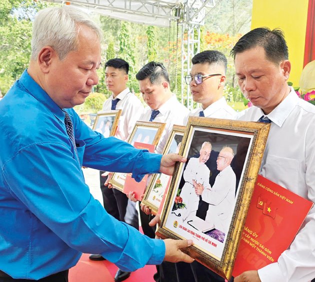 Ông Võ Khắc Thái - Phó Chủ tịch Thường trực LĐLĐ TPHCM - tặng quà lưu niệm cho các đảng viên được kết nạp tại Côn Đảo. Ảnh: NAM DƯƠNG