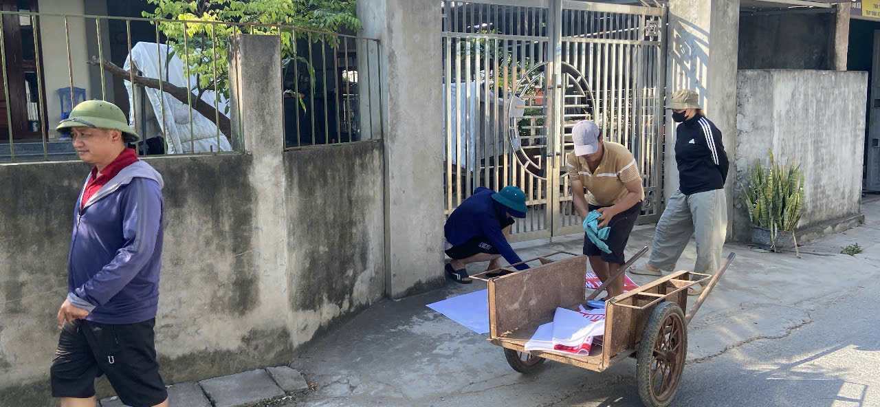 Anh Nguyễn Đình Giang cùng thanh niên trong thôn tham gia dán biển tuyên truyền vận động người dân.