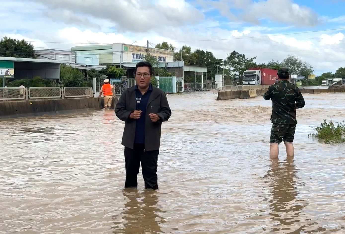 Reporters lead the scene in the deep flooded area on National Highway 1, causing traffic disruption. Photo: DUY TUAN