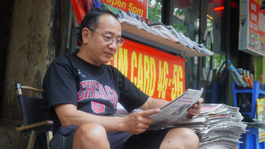 Bên những chồng báo được sắp xếp ngay ngắn, ông Đặng Hữu Phán tranh thủ đọc những tin tức mới nhất trước khi đón khách.