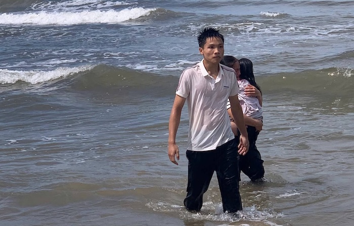 Em Lê Đức Trung cùng cháu bé vào bờ an toàn. Ảnh: Hàn Nguyên