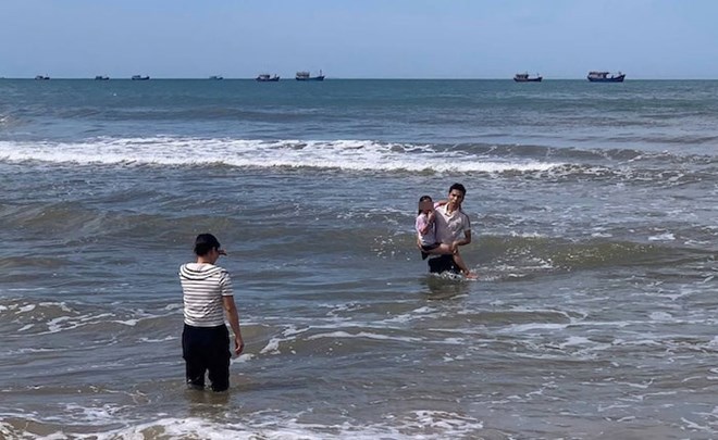 Bé gái bị sóng cuốn trôi xa bờ cả trăm mét được nam sinh ứng cứu, đưa vào bờ. Ảnh: Hàn Nguyên