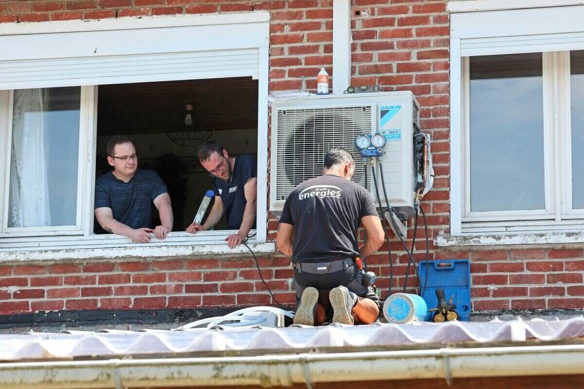 A air conditioner installer is working in the hot sun in France. Photo: AFP