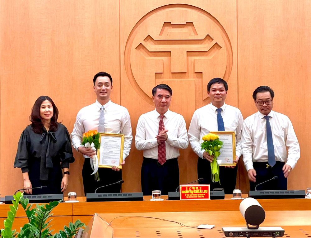 Vice Chairman of Hanoi People's Committee Nguyen Xuan Luu (middle) presents decisions and flowers to congratulate the appointed officials. Photo: Huong Ly