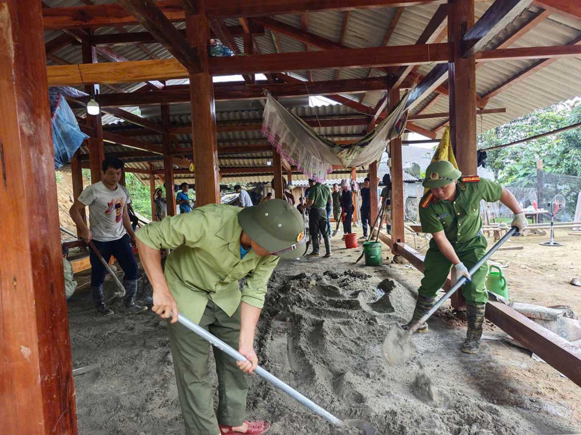 Công an xã Phong Dụ Thượng chung tay giúp người dân hoàn thiện nền nhà. Ảnh: CA Lào Cai