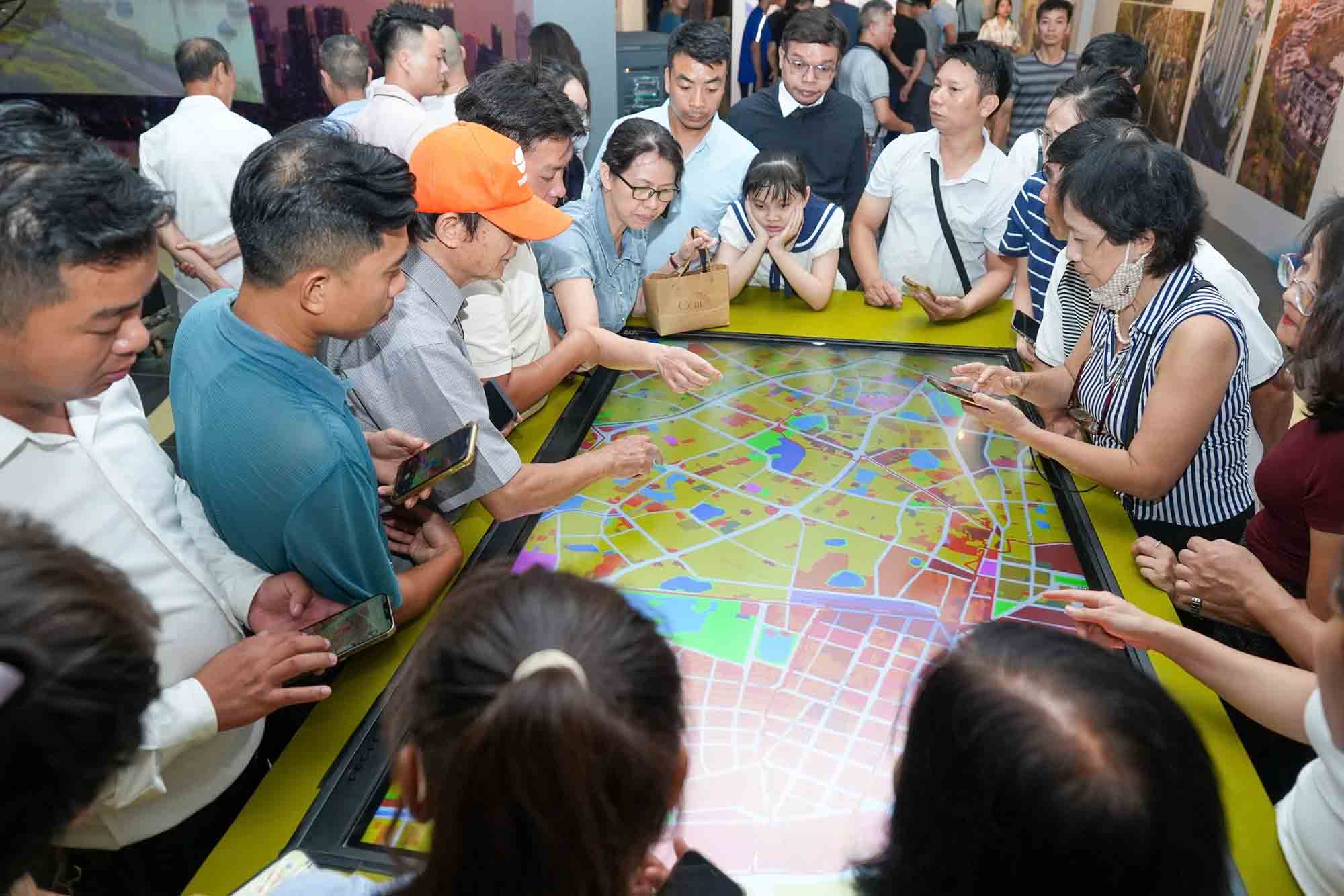 La gente consulta los proyectos de planificación de subzonas en el área de la ciudad de Hanoi en el piso 4 del Museo de Hanoi, tarde del 29 de junio. Foto: Huu Chanh