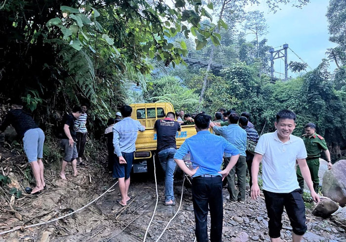 Các cán bộ công an và người dân dùng dây cáp để kéo ô tô tải lên bờ. Ảnh: CACC   