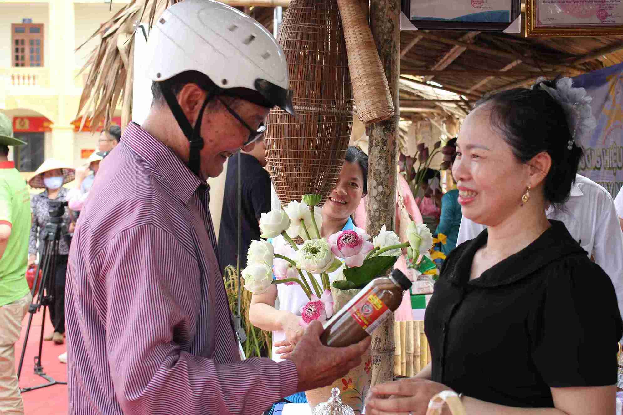Bà Phạm Thị Hoa giới thiệu các sản phẩm đặc trưng của địa phương tới người dân tham quan ngày hội. Ảnh: Mai Hương