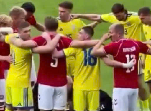 Players together form a circle to protect Christian Eriksen while he is being given first aid on the field. Photo: Cut from video