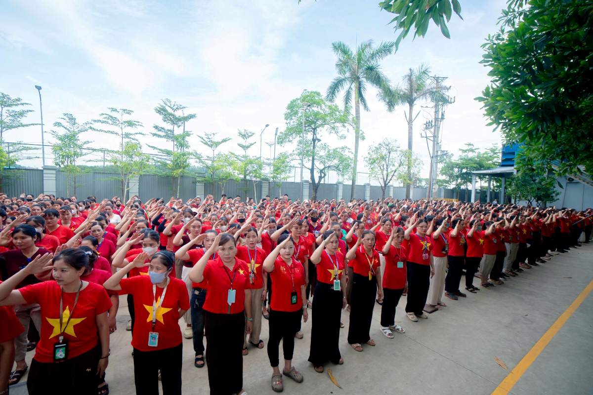 Hàng trăm công nhân lao động Công ty TNHH Giầy Venus Việt Nam tham gia nghi lễ chào cờ, hát Quốc ca trong ngày làm việc đầu tuần. Ảnh: Quách Du
