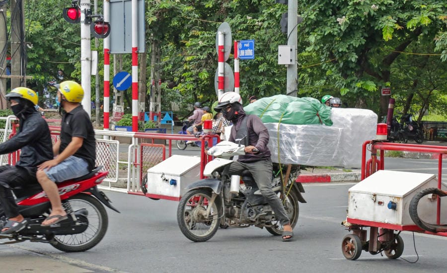 Les feux sont rouges, les barrières sont tirées, mais de nombreuses personnes à Hanoï essaient toujours de traverser la voie ferrée. Photo: Thế Kỷ