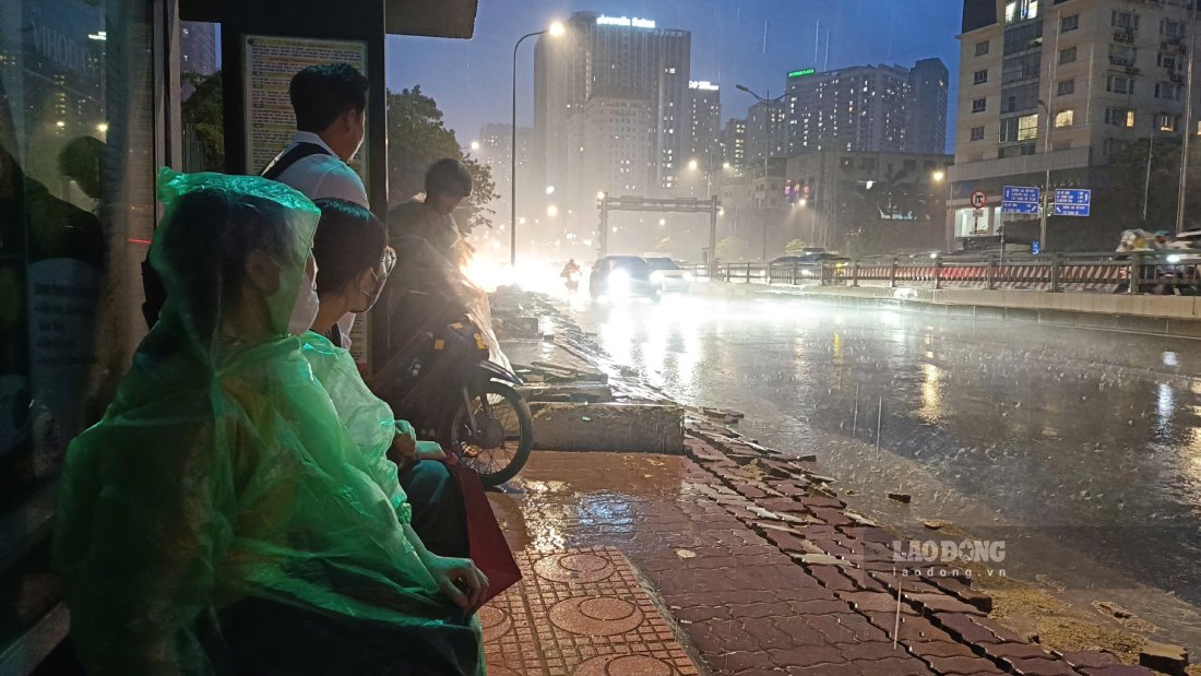 Khoảng 19h, tại khu vực đường Phạm Văn Đồng mưa lớn vẫn tiếp diễn khiến việc đi lại bị gián đoạn, nhiều người dân vất vả chờ xe buýt sau giờ tan tầm.