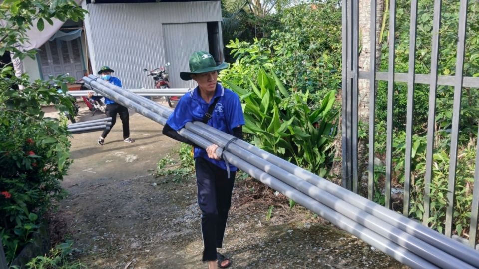 Students of Cuu Long University and local forces participate in the construction of a clean water pipeline. Photo: Hoang Loc