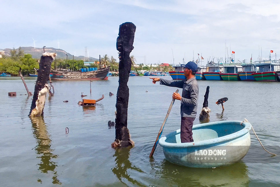 Ngư dân Lê Văn An (trú xã Cát Tiến) bên chiếc tàu chỉ còn trơ khung sau vụ cháy. Ảnh: Hoài Phương