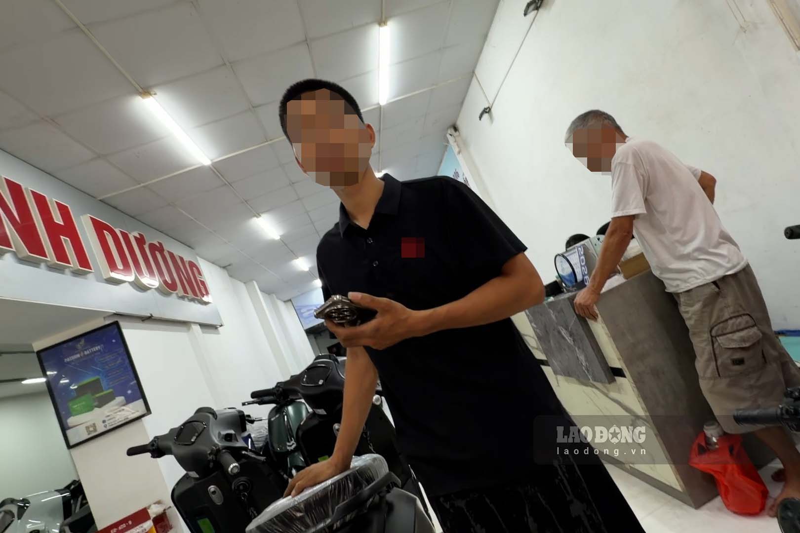 Nam nhân viên cửa hàng xe máy điện tại số 929 Ngãi Cầu, An Khánh tư vấn cho phóng viên cách độ pin xe điện. Ảnh: Nhóm phóng viên.