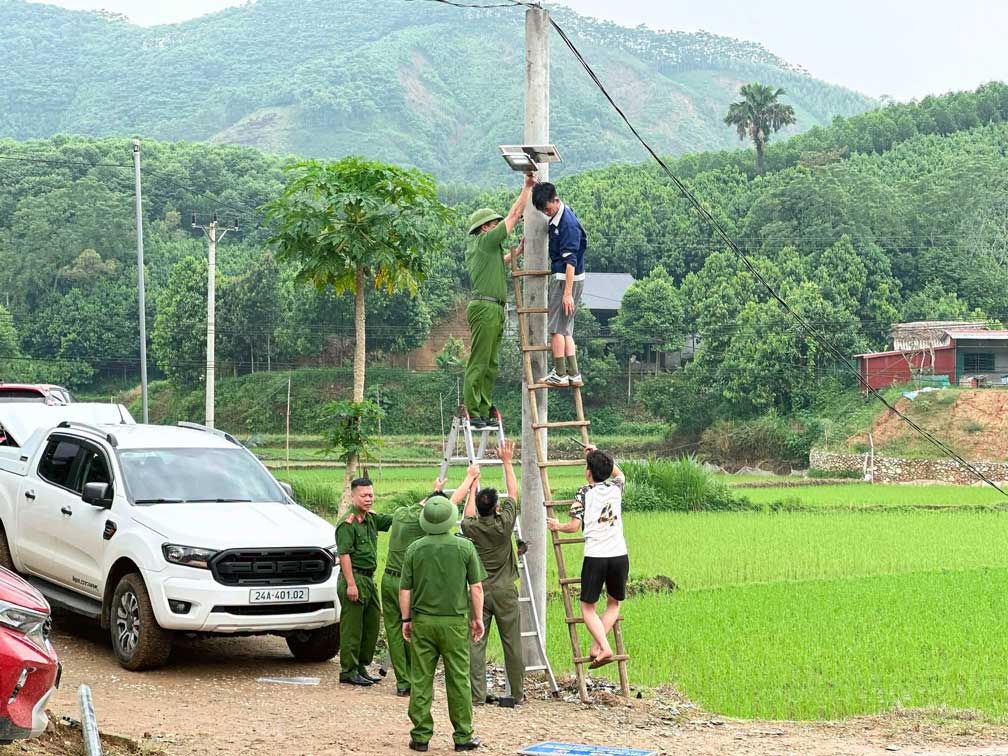 Les forces de police coopèrent avec les habitants pour installer des systèmes d'éclairage public sur la route. Photo: Police de la commune de Yên Bình