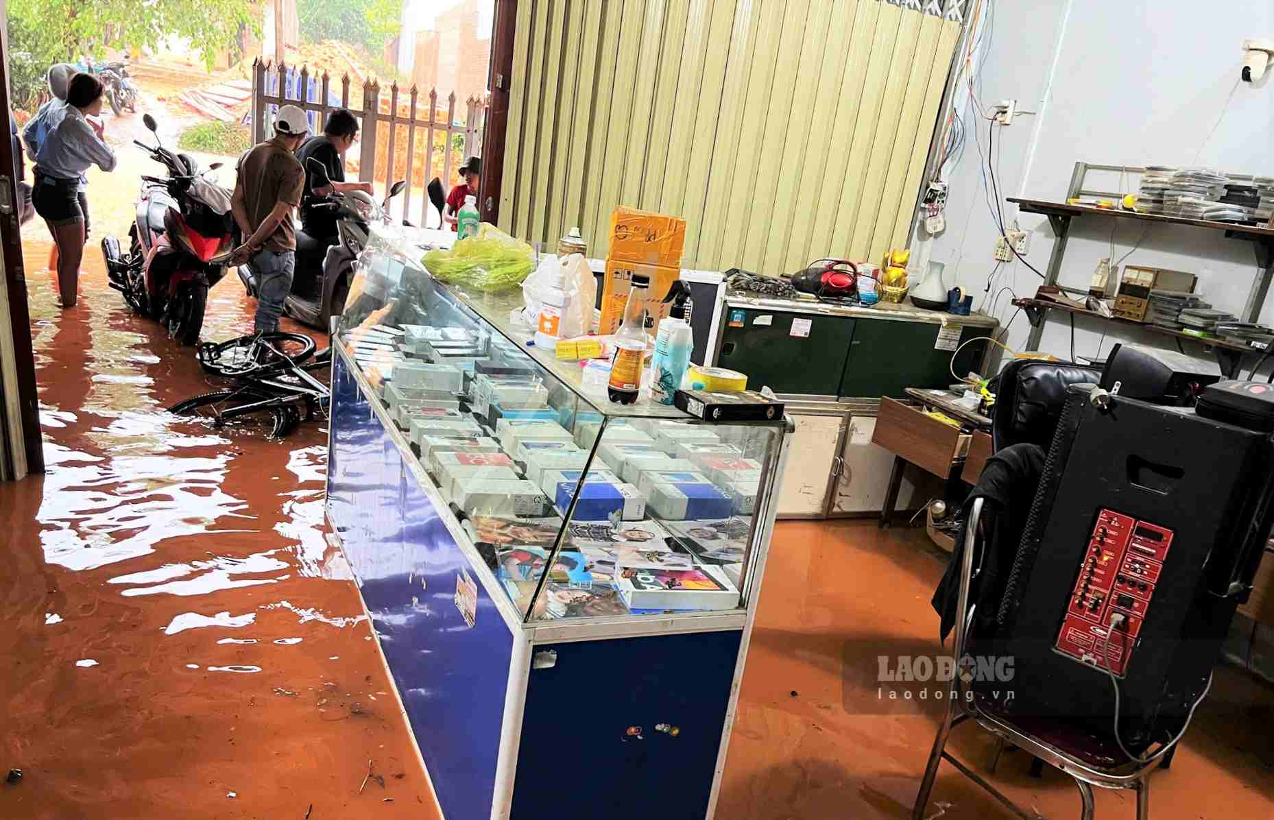 Nước tràn vào ngập tiệm điện thoại của một hộ dân ven đường. Ảnh: Phúc Khánh 