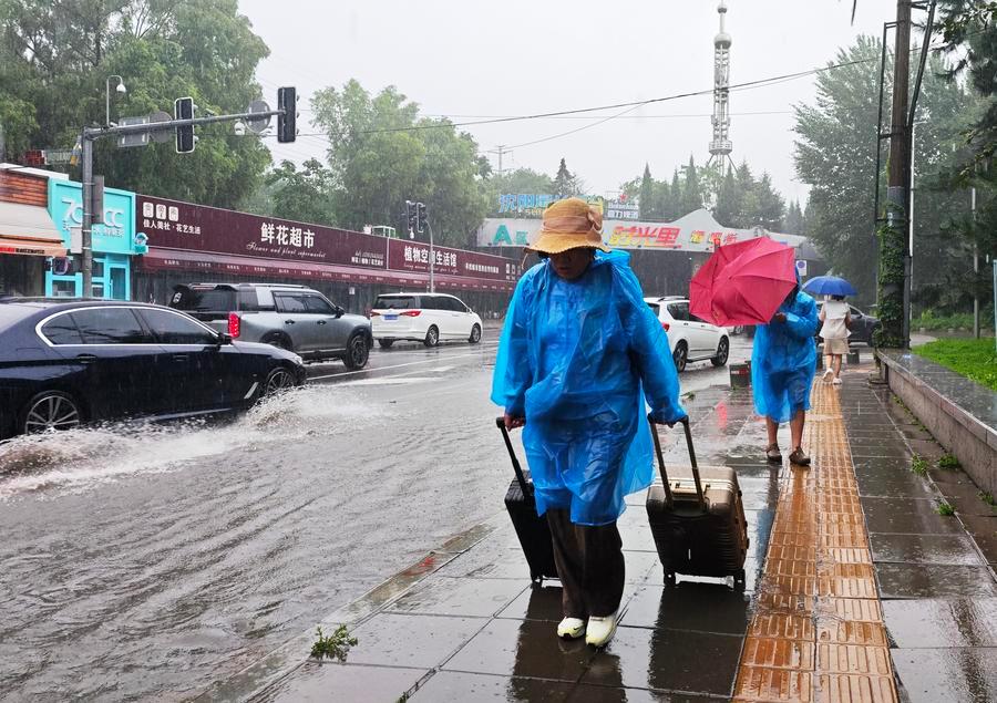 People walking in the rain in Shenyang city (Liaoning province, Northeast China) on July 13. Photo: Xinhua
