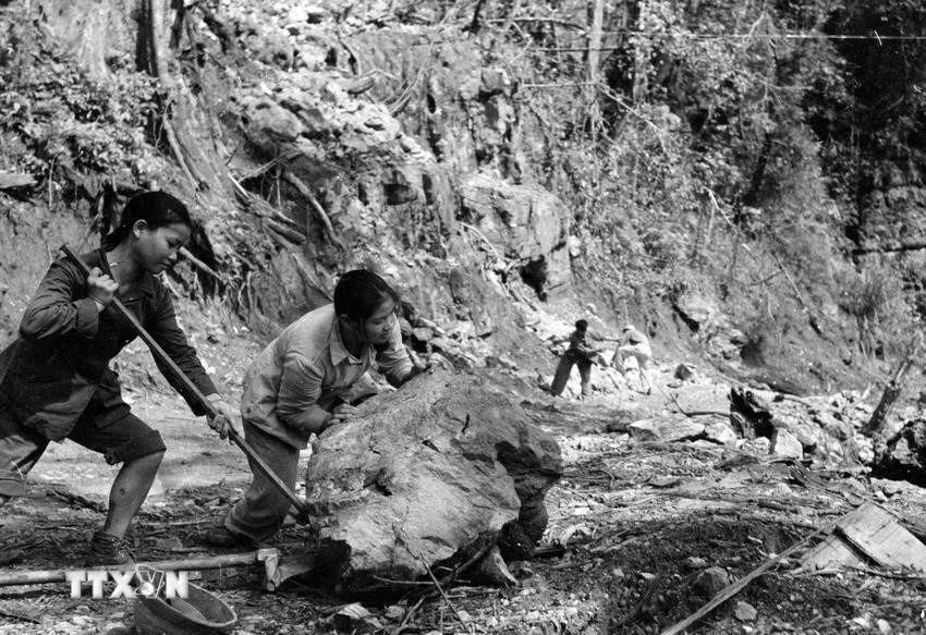 Volunteer youth forces push stones, paving roads for vehicles to pass through Truong Son road. Photo: Huu Khoi/VNA