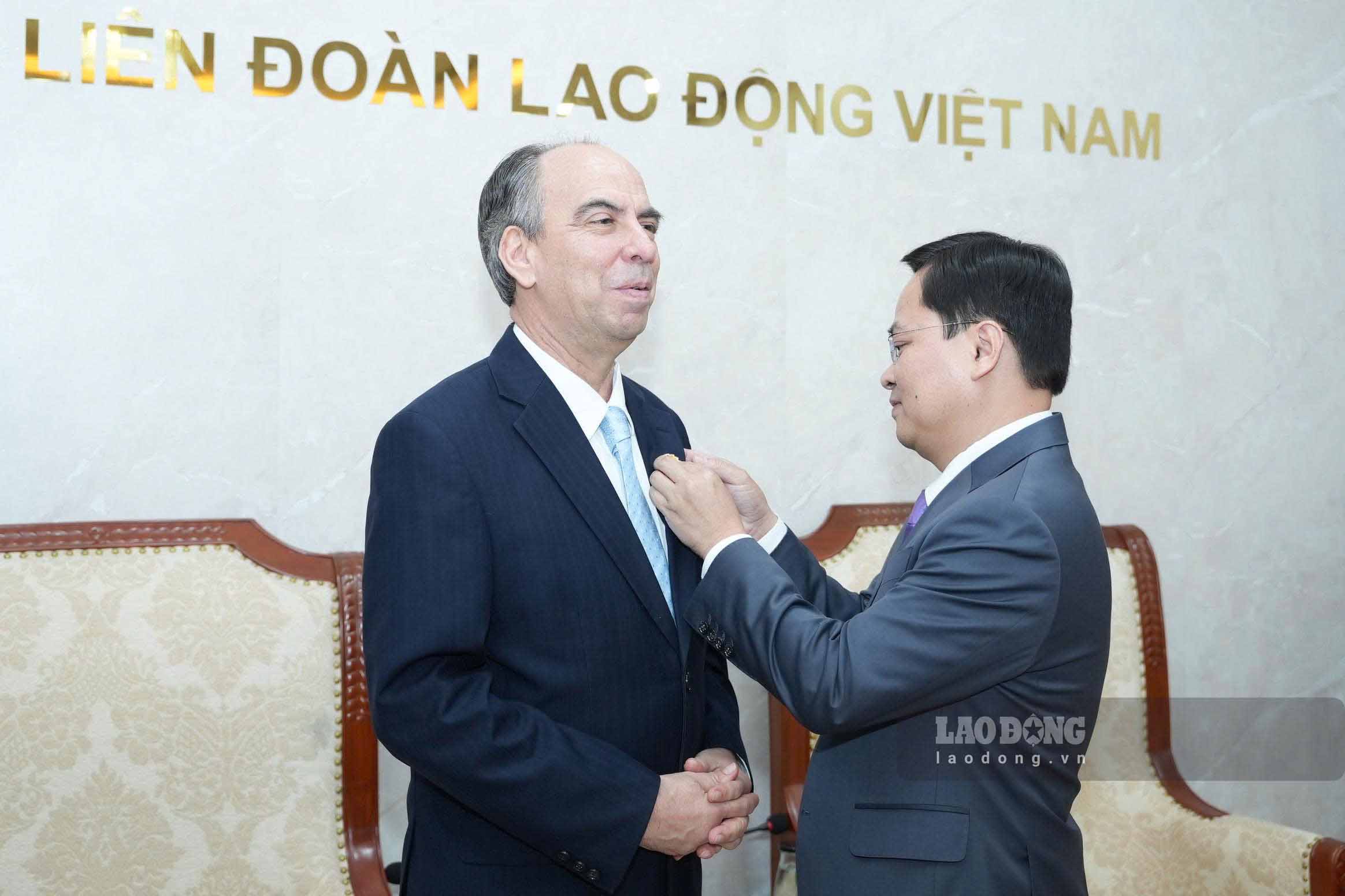 Ông Nguyễn Anh Tuấn, Ủy viên Trung ương Đảng, Chủ tịch Tổng LĐLĐVN gắn tặng logo Đại hội XIV Công đoàn Việt Nam tới ông Rogelio Polanco Fuentes, Đại sứ Cuba tại Việt Nam (bên trái). Ảnh: Hữu Chánh