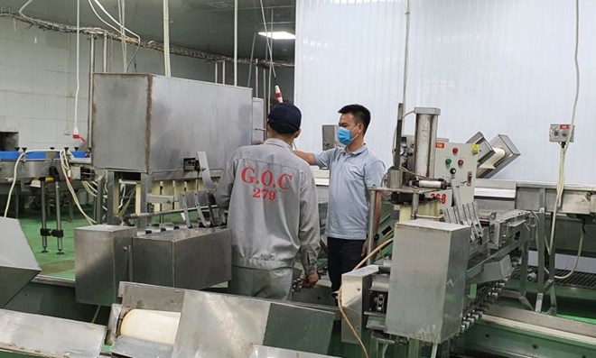Anh Lương Xuân Huy (đeo khẩu trang) đang hướng dẫn công nhân vận hành máy móc tại công ty. Ảnh: Nhân vật cung cấp.