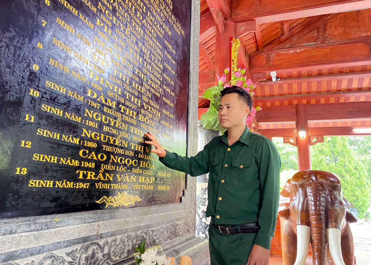 Ông Phan Trọng Lộc - Giám đốc Ban Quản lý Khu di tích lịch sử quốc gia Truông Bồn - bên tấm bia đá khắc tên 13 anh hùng liệt sĩ thanh niên xung phong tại khu mộ chung. Ảnh: Khu di tích Truông Bồn