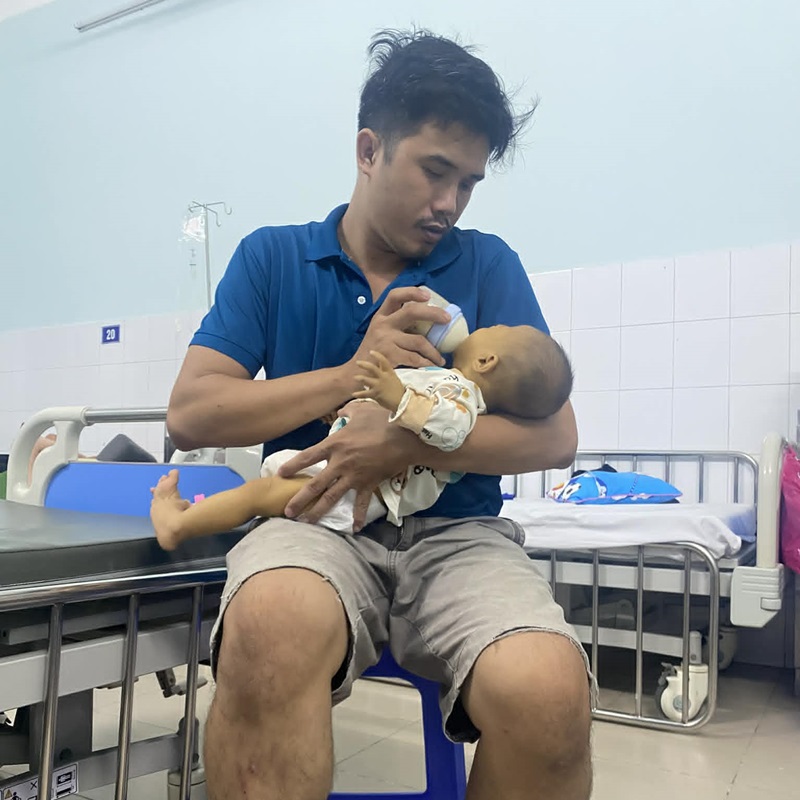 Mr. Khanh takes care of his daughter at the hospital. Photo: Family provided
