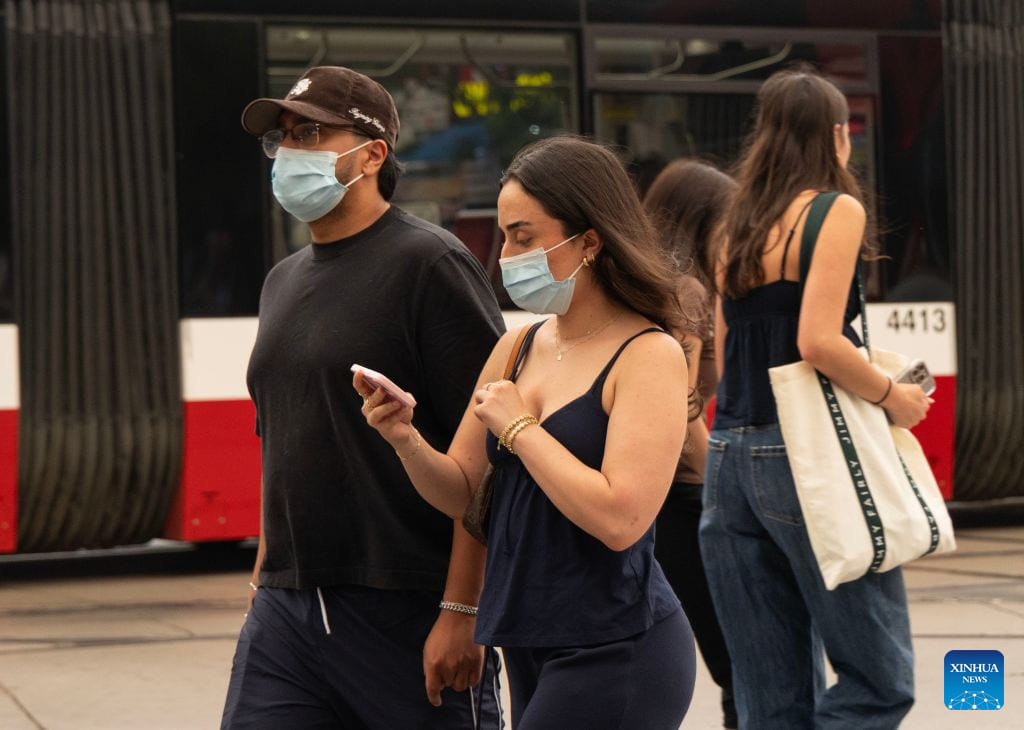 Người dân đeo khẩu trang trên đường phố Toronto, Canada, khi khói từ các vụ cháy rừng bao phủ bầu trời thành phố, ngày 15.7.2026. Ảnh: Xinhua