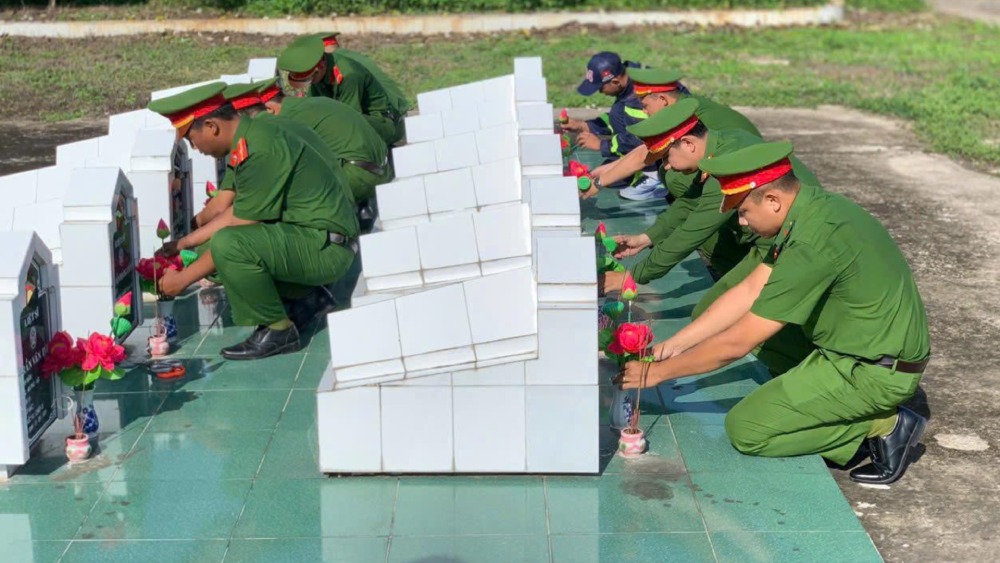 Các lực lượng làm vệ sinh, chỉnh trang khuôn viên, thay hoa mới ở những phần mộ. Ảnh: Tiến Dũng/ Công an An Giang