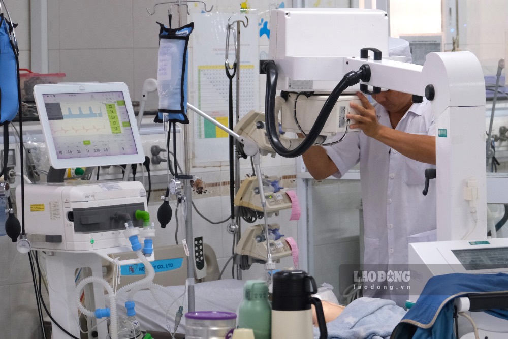 Medical staff of the ICU Department adjust mobile X-ray machine for a patient over 6 months old right at the hospital bed. Photo: Phong Linh.
